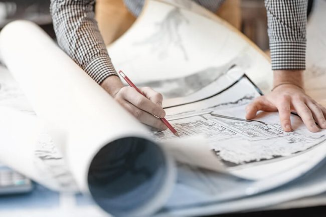 Close up of hands holding a pencil and reviewing technical drawings